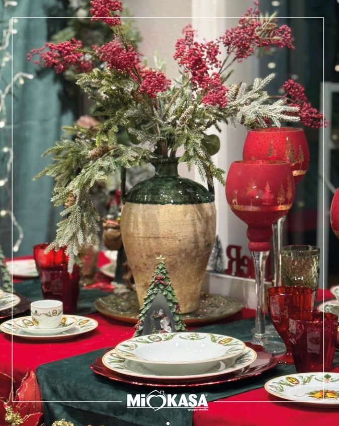 Tavola di Natale rosso e verde con vaso rustico, calici rossi e centrotavola di bacche