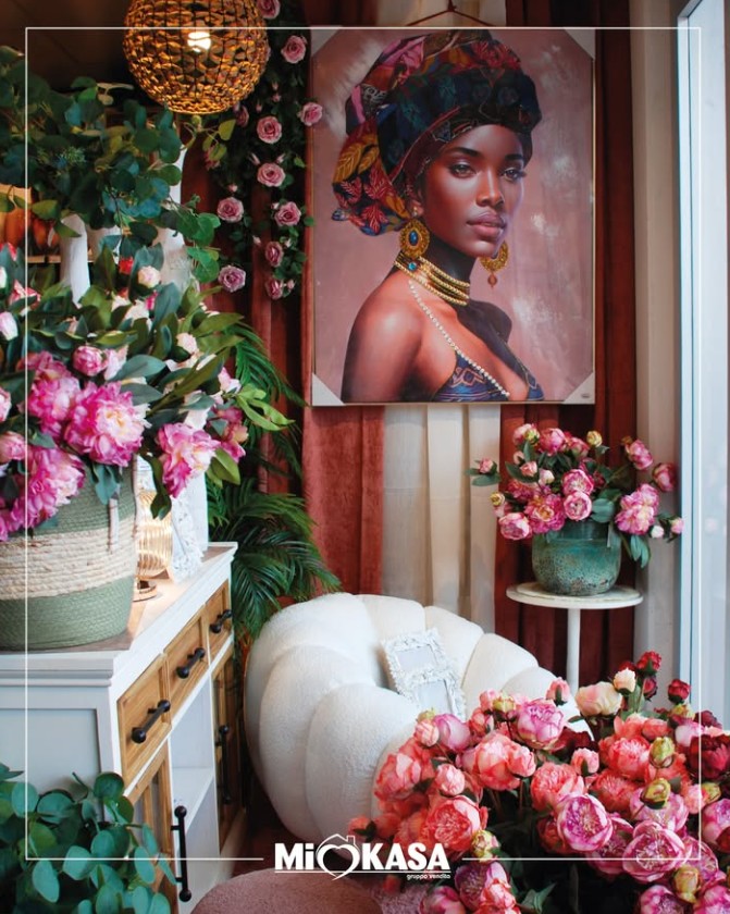 Allestimento bohémien con quadro decorativo, peonie rosa e poltrona panna